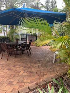 a patio with a table and chairs under a blue umbrella at Beachfront at Silver Sands Hervey Bay in Hervey Bay