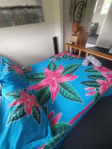 Una cama con un edredón azul con flores rosas. en Stanmore Bay Beach House, en Whangaparaoa