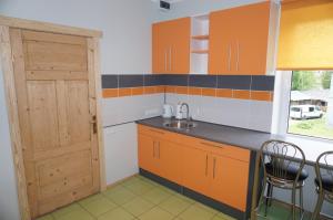 a kitchen with orange cabinets and a sink and a door at Holiday Apartment in Alūksne