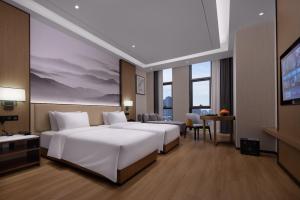a hotel room with two beds and a television at Metropark Hotel Wuhan in Wuhan