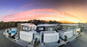 eine Gruppe von Häusern mit Sonnenuntergang im Hintergrund in der Unterkunft Essence Peregian Beach Resort - Marram 3 Bedroom Luxury Home in Peregian Beach