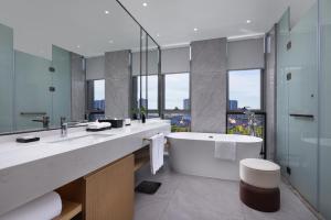 ein Badezimmer mit einer großen Badewanne und einem großen Spiegel in der Unterkunft Metropark Hotel Wuhan in Wuhan