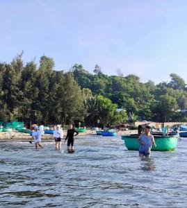 un grupo de personas de pie en el agua cerca de los barcos en Sea view homestay villa, en Ấp Ðại Tài (2)