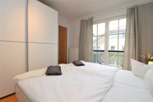 ein weißes Bett in einem Zimmer mit einem großen Fenster in der Unterkunft Birkenhof App 74 in Wustrow