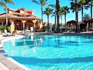 ein großer Pool vor einem Haus mit Palmen in der Unterkunft Family Friendly Home, South-facing Pool,Spa, Gated Resort near Disney -928 in Davenport