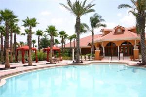 ein Pool mit Palmen und ein Gebäude in der Unterkunft Family Friendly Home, South-facing Pool,Spa, Gated Resort near Disney -928 in Davenport