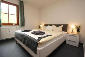 Un dormitorio con una gran cama blanca con ventana. en Oewern Diek App 03, en Wustrow