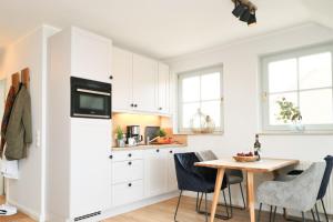 una cucina con mobili bianchi e un tavolo con sedie di Oewern Diek App 12 a Wustrow