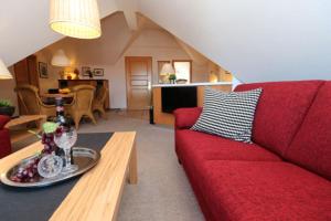 a living room with a red couch and a table at Oewern Diek App 09 in Wustrow +10 photos