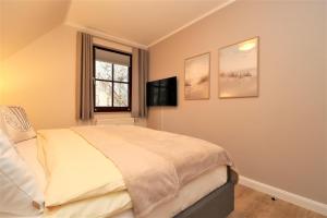 ein Schlafzimmer mit einem Bett und einem TV an der Wand in der Unterkunft Oewern Diek App 58 in Wustrow