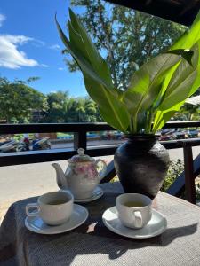 a table with two cups of tea and a vase at Villa Namkhan Heritage in Luang Prabang