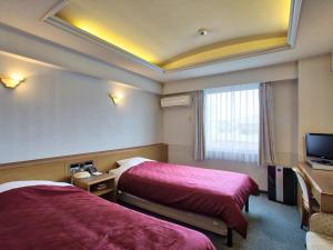 pokój hotelowy z 2 łóżkami i telewizorem z płaskim ekranem w obiekcie Okinawa Hotel w mieście Naha