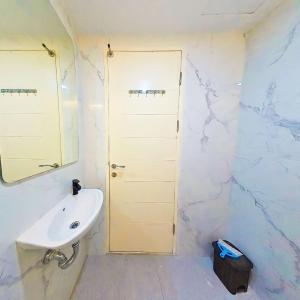 een witte badkamer met een wastafel en een spiegel bij Ayodhya Studio at Benson Tower in Lontar