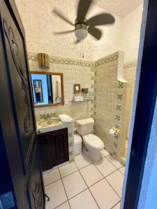 a bathroom with a toilet and a ceiling fan at Bttm floor beachfront condo in Half Moon Bay Akumal in Akumal