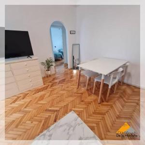 sala de estar con mesa, TV y suelo de madera. en De La Montaña • Palermo en Buenos Aires