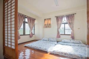 a bedroom with two beds and two windows at Huan Bei 88 Homestay in Jincheng
