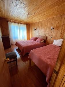 um quarto com 2 camas num quarto de madeira em Cabaña en pelluhue 5 personas em Pelluhue