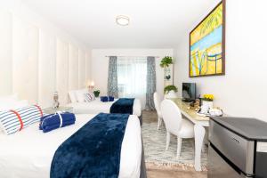 a hotel room with two beds and a desk at 6768 Collins Miami Stays in Miami Beach