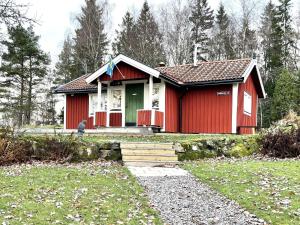 een rood huis met een groene deur in een tuin bij Holiday home PRÄSSEBO II in Eckerud