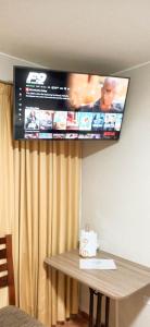 a flat screen tv hanging on a wall above a table at Habitación 2 camas a pasos del Aeropuerto Lima in Lima