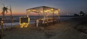 cabañas Juakianna في تولو: خيمة على الشاطئ مع طاولات وكراسي