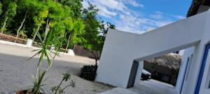 a white building with a door in the sand at Posada Mykonos in Bacalar