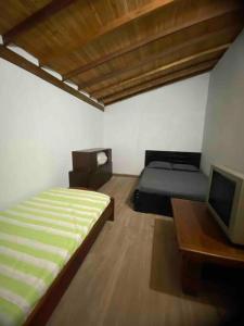 1 dormitorio con 1 cama, escritorio y TV en Casa de campo El bosque de julia en Medellín