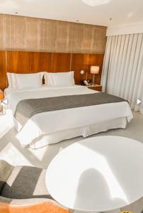 Un dormitorio con una gran cama blanca y una mesa en Hotel Nacional RJ - Vista Mar, en Río de Janeiro