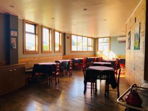 a dining room with tables and chairs and windows at Esquina Huella Patagónica in Coihaique