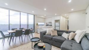 een woonkamer met een bank en een tafel bij Central Canterbury Charm Sky View Free Parking in Sydney