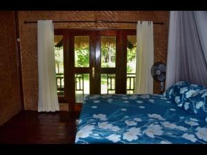 a bedroom with a bed with a blue comforter and a window at AMIGOS BUNGALOWS GILI MENO in Gili Meno +41 photos