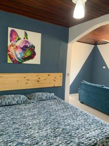 1 dormitorio con 1 cama con una pintura en la pared en Suite 237 en Itanhaém