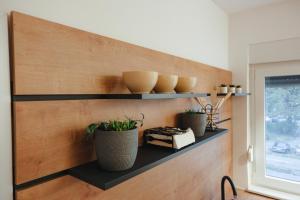 un mur avec des étagères avec des plantes et des vases sur lui dans l'établissement Apartment Exclusive - Self check In, à Osijek