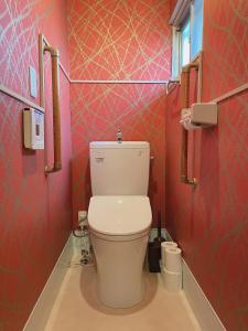a bathroom with a toilet in a red wall at East Shin-Osaka Hotel Apartment in Osaka