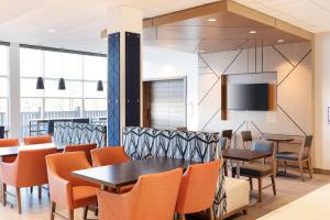 a dining room with tables and chairs and a flat screen tv at Holiday Inn Express Hotel & Suites Vineland Millville, an IHG Hotel in Vineland