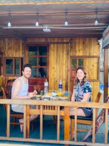 un hombre y una mujer sentados en una mesa en Eco Floating Farm Stay Cai Beo en Cat Ba