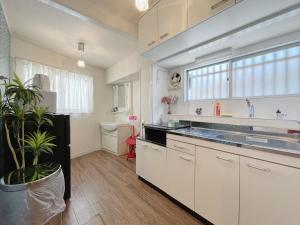 a kitchen with white cabinets and a potted plant at East Shin-Osaka Hotel Apartment in Osaka
