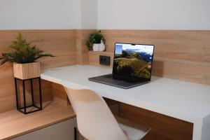 Apartment Exclusive - Self check In في أوسييك: يوجد جهاز كمبيوتر محمول على مكتب أبيض مع كرسي