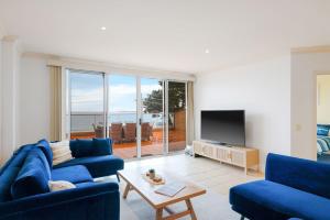 a living room with two blue couches and a television at Beachfront Bliss - shared indoor pool & spa in Cowes