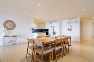 a kitchen and dining room with a wooden table and chairs at Beachfront Bliss - shared indoor pool & spa in Cowes