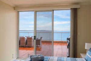 a bedroom with a sliding glass door with a view of the ocean at Beachfront Bliss - shared indoor pool & spa in Cowes