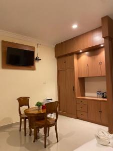 uma cozinha com mesa e cadeiras e uma televisão na parede em BERYL HOMESTAY em Tarutung