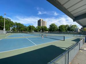 un groupe de personnes jouant au tennis sur un court de tennis dans l'établissement Charming and cozy apartment in New Jersey close to all the fun 10 minutes to NYC, à West New York