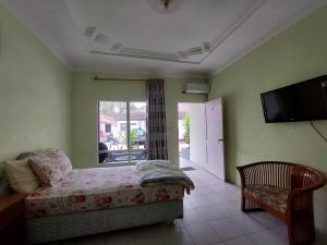 een slaapkamer met een bed, een tv en een stoel bij Grand Syariah Guest House Humanitas in Pematangsiantar