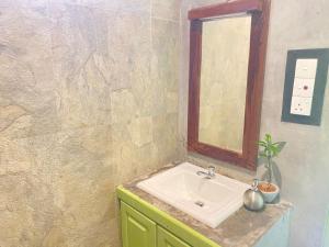 ein Bad mit einem Waschbecken und einem Spiegel in der Unterkunft Maina Home's Gₐₗₗₑ in Bope
