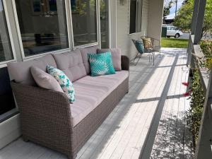 a wicker couch sitting on the porch of a house at Barefoot Bungalow in Tomakin
