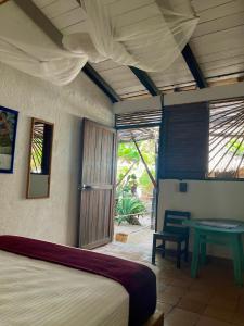 a bedroom with a bed and a table and a window at Posada Mexico in Zipolite