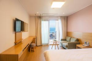 Habitación de hotel con cama, TV y sofá en Sims Hotel, en Jeju