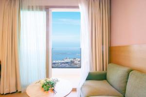 済州市にあるSims Hotelのソファと大きな窓のあるリビングルーム