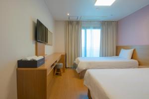 a hotel room with two beds and a television at Sims Hotel in Jeju